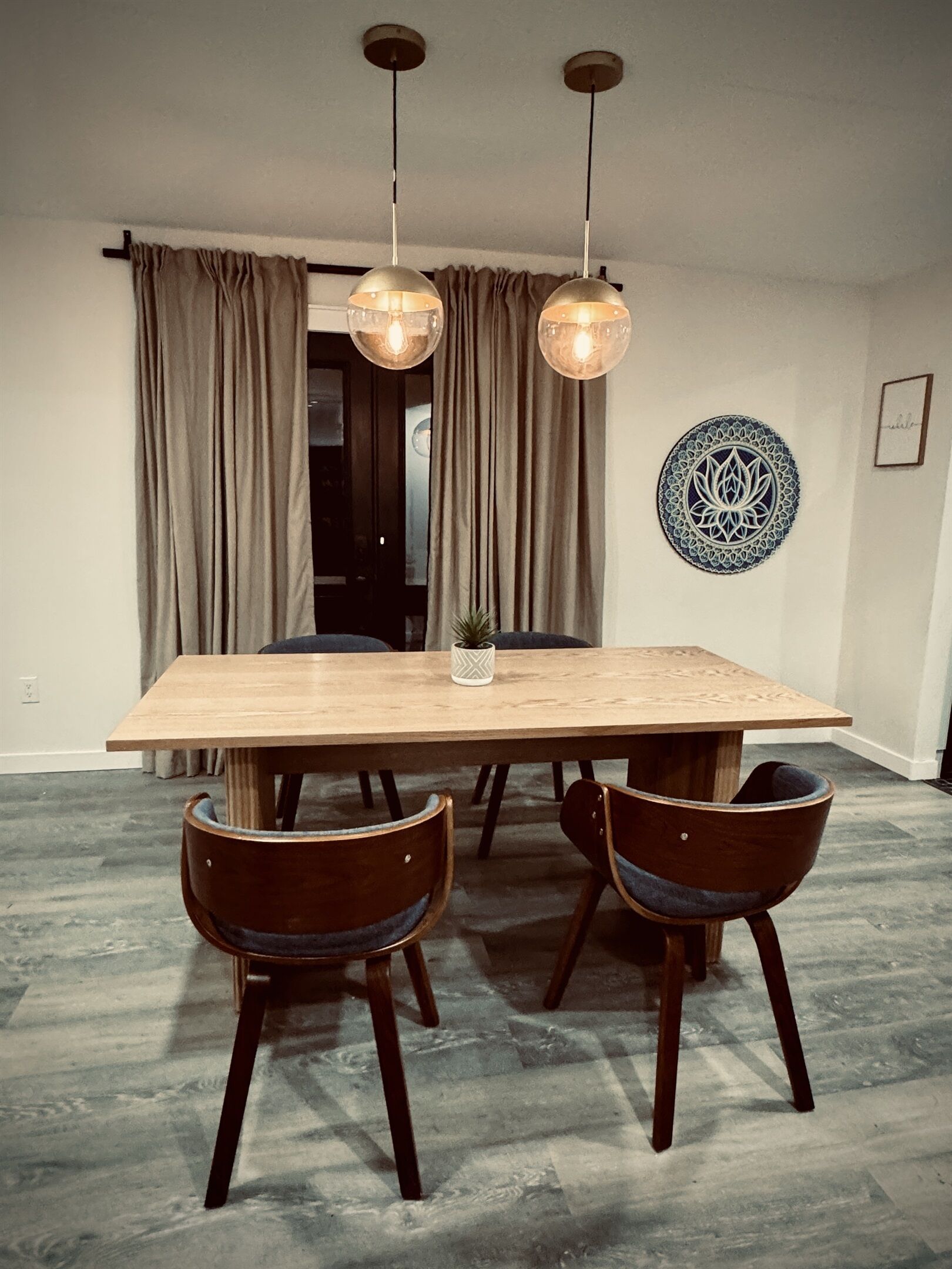 Een eethoek met een houten tafel, vier stoelen en hanglampen.