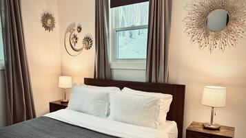 A neatly made bed with white linens, two bedside tables with lamps, and decorative wall art.