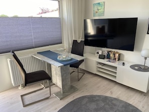 Un salon moderne équipé d’un téléviseur, de sièges, d’une table à manger et d’un radiateur.
