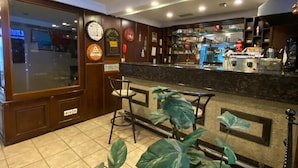 Zona de bar con mostrador, taburetes y un reloj en la pared.