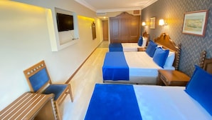 Habitación de hotel con dos camas, televisión, escritorio y una silla.