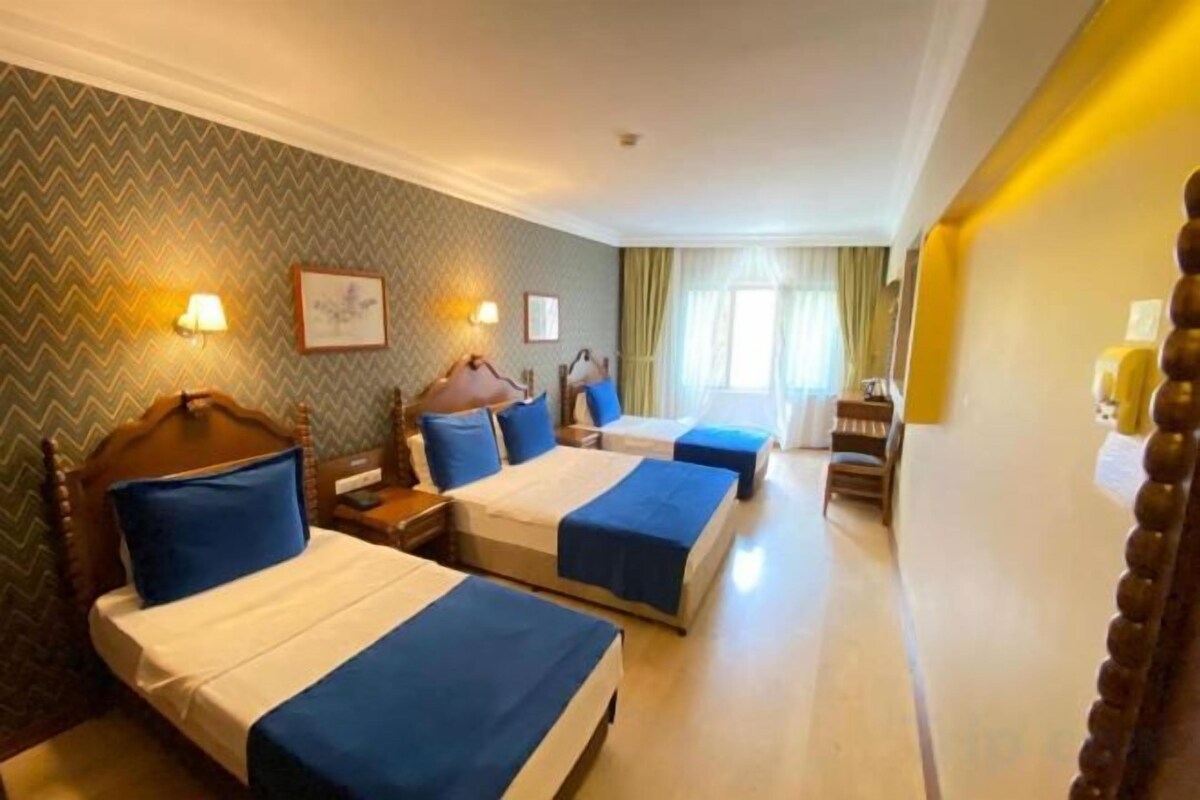 Een hotelkamer met twee bedden, een houten hoofdbord, een nachtkastje, een bureau en een stoel.