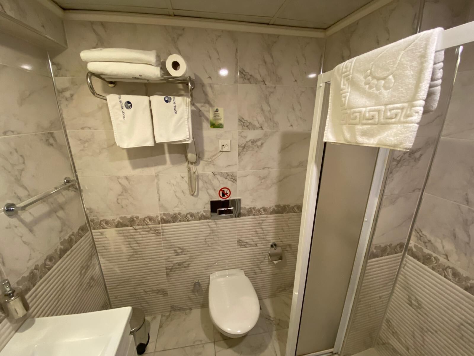 A bathroom with a toilet, a sink, a shower with a glass door, and a towel rack with towels.