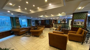 Un hall amplio con varios sofás y sillones, una zona de bar y un ventanal con vistas.