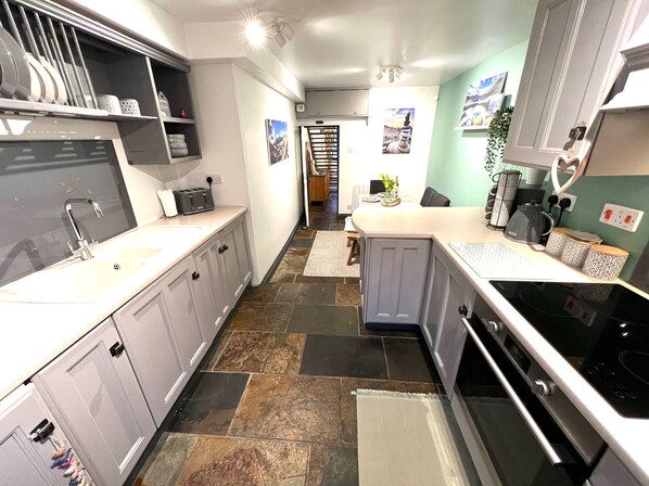 A modern kitchen with grey cabinets, a black stove, and a tiled floor. - Cottage - Sleeps 4 - Pet Friendly - Terrace (Caernarfon)