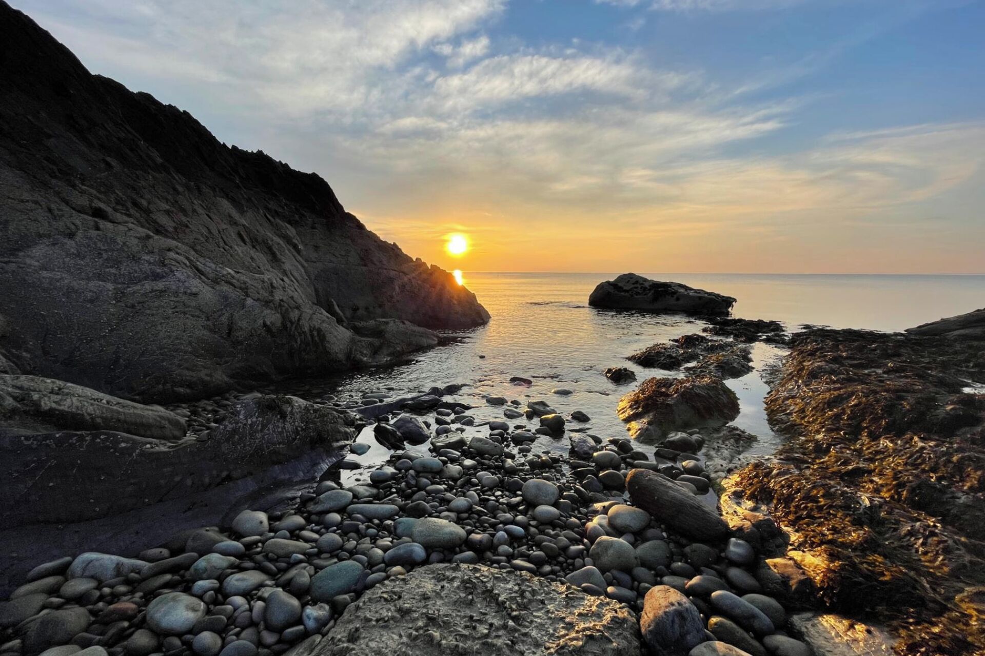 Una costa rocosa con un atardecer al fondo.