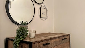 Een houten dressoir met laden, een bloempot en een kaars erboven.