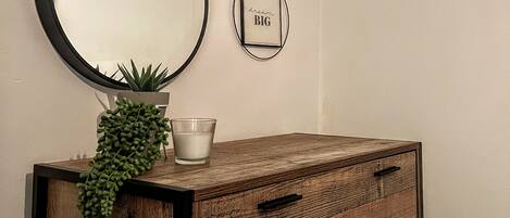 A wooden dresser with drawers, a potted plant, and a candle on top.