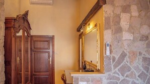 Une salle de bain avec un mur en pierre, une porte en bois et un miroir doté d’un cadre doré.