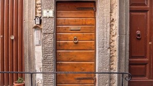 Une porte en bois, dotée d’une poignée en métal et d’une plaque fixée au-dessus, le tout intégré dans un mur de pierre.