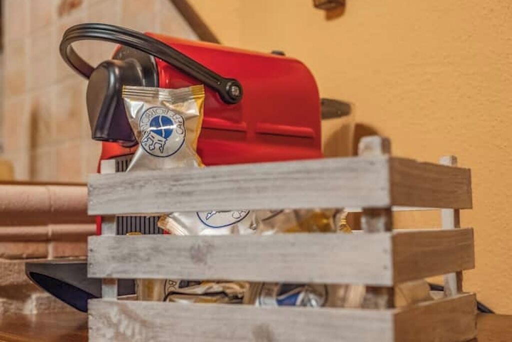Un appareil de couleur rouge, peut-être une machine à café, devant lequel se trouve une caisse en bois.