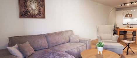 A modern living room with a sectional sofa, a round coffee table, and a dining area with a table and chairs.