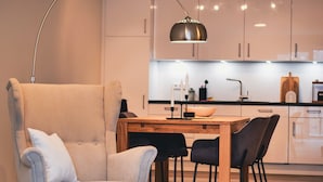 Una cocina moderna con armarios blancos, una mesa de comedor de madera y sillas negras.