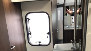 A compact bathroom with a toilet, a sink, and a window. - ford zefiro 675 6 berth (wigan)