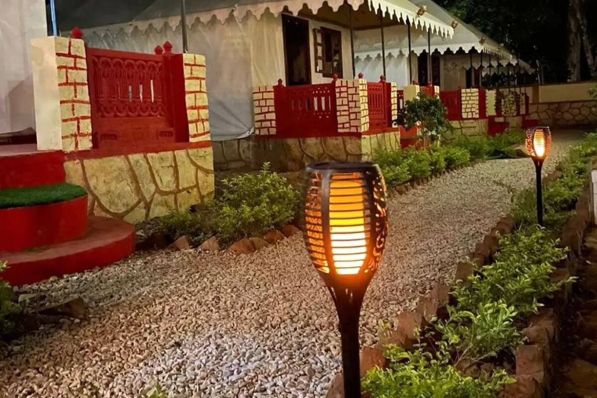 A traditional-style building with a tiled roof and red accents, surrounded by a gravel path and greenery.