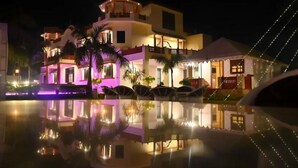 A multi-story hotel with a reflective pool in front.