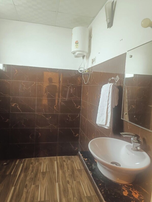 Une salle de bain avec un plancher en bois, un lavabo blanc, un miroir et une serviette accrochée au mur.