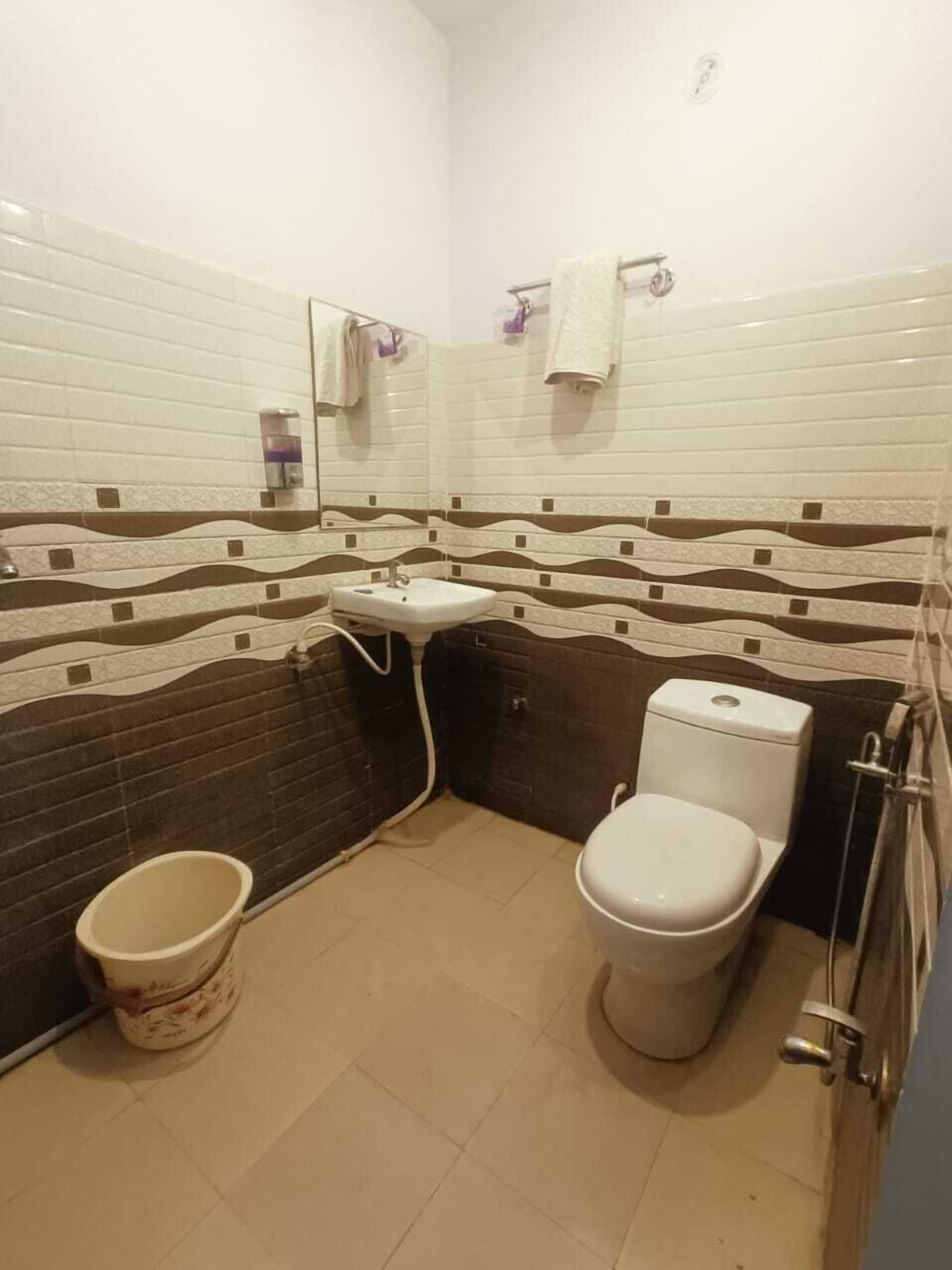 Egy fürdőszoba, amelyben fehér mosdókagyló, WC és zuhanyzó található.
