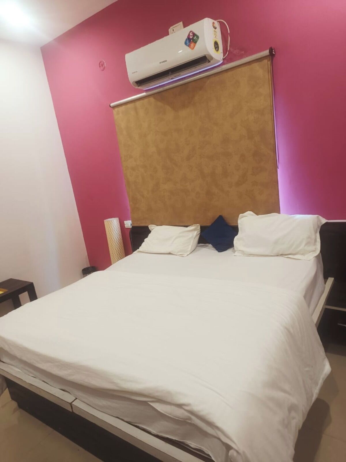 Un dormitorio con cama, aire acondicionado de pared y mesita de noche.