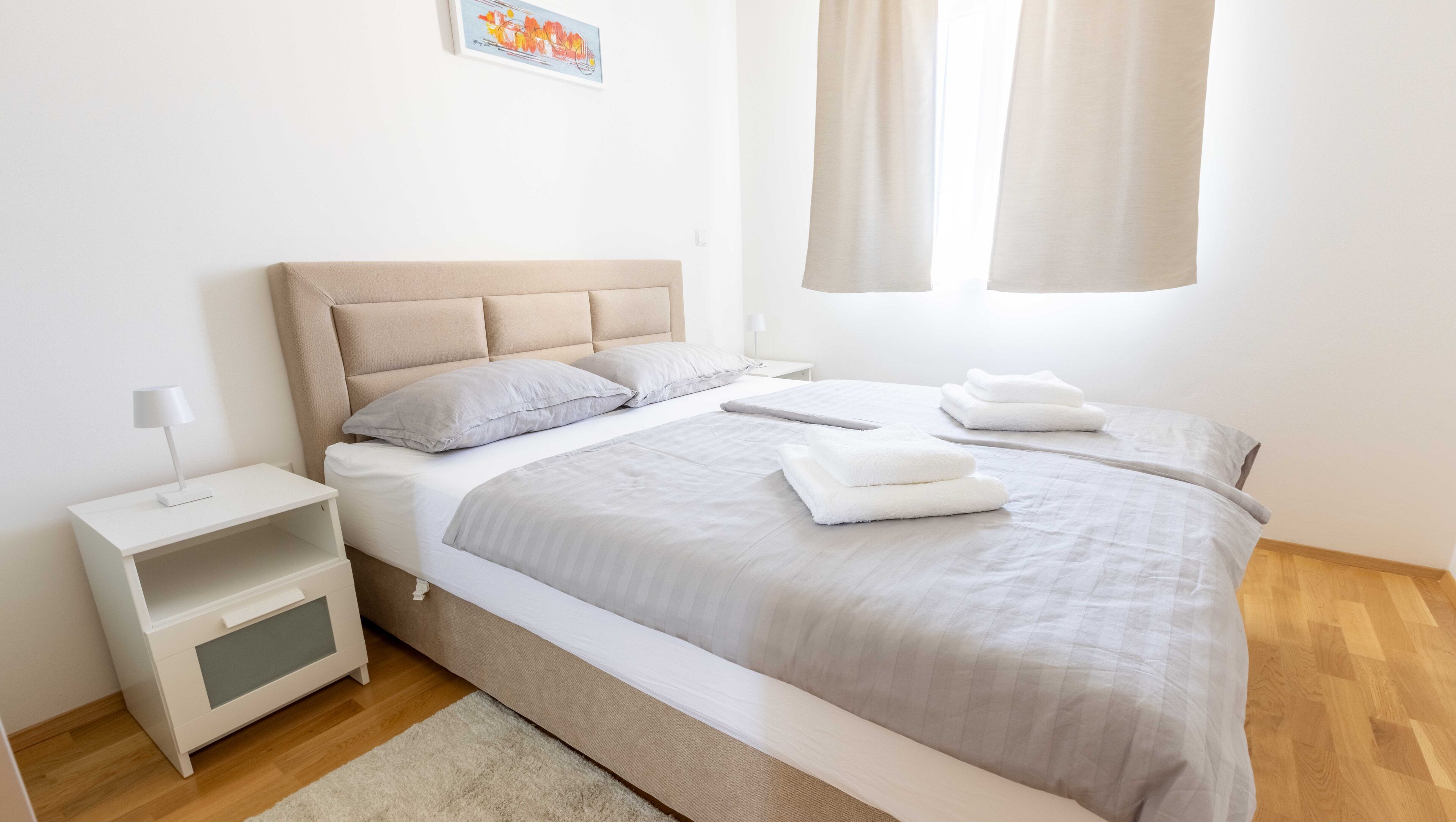 Une chambre moderne avec un grand lit, une table de chevet et une commode.