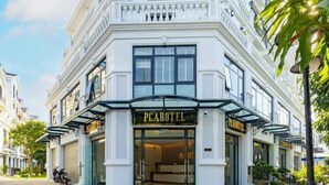 A classic building with a prominent "PEACHOTEL" sign at the entrance, featuring a grand entrance and a balcony with railings. - PCA Hotel 1- Vinhomes Ocean Park (Hanoi)