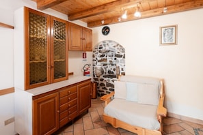 A room with a stone arch, wooden cabinets, a bed, and a clock on the wall.