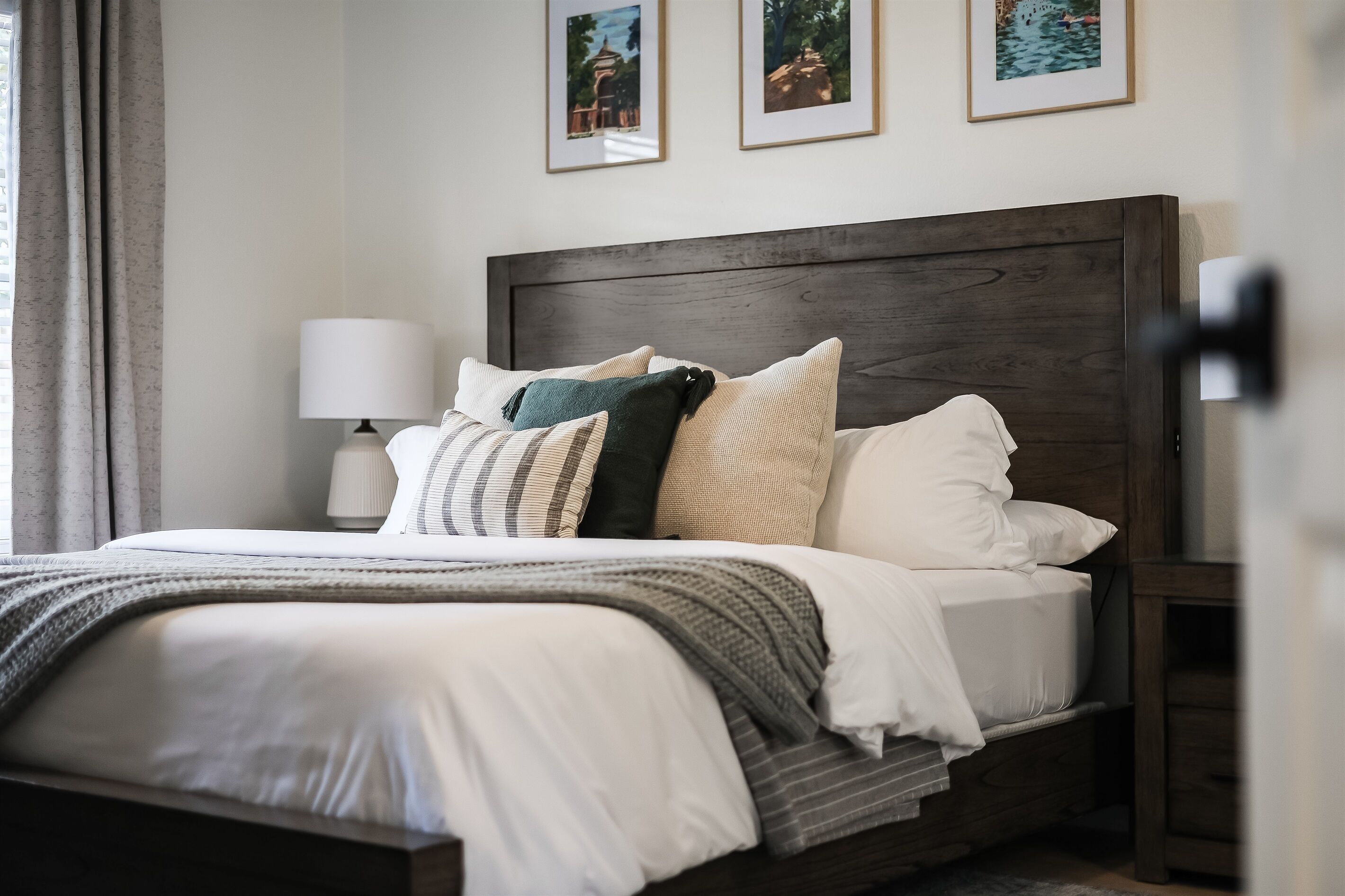 A neatly made bed with a wooden headboard, a bedside lamp, and a nightstand.