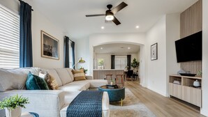 Ein modernes Wohnzimmer mit Sofa, Couchtisch und Fernseher auf einer Holzkommode.