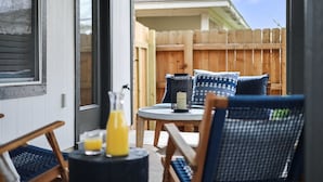 Eine Terrasse mit einem runden Tisch, zwei Stühlen und einem Holzzaun im Hintergrund.