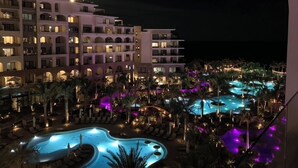 Un hôtel doté de nombreux balcons, d’une piscine et de palmiers.