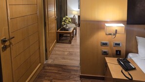 Une chambre d’hôtel avec une armoire en bois, une table de chevet avec une lampe, un téléphone et un lit.