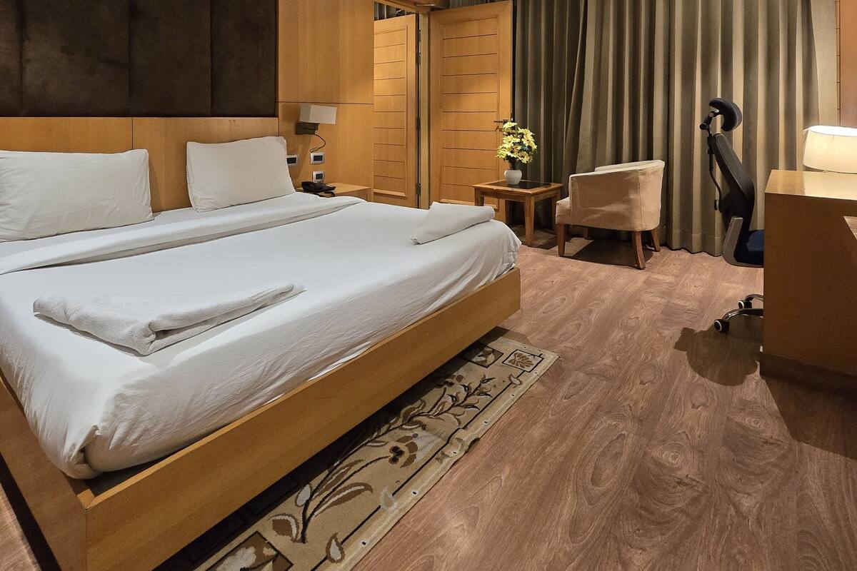 Habitación de hotel con una cama grande, un escritorio, una silla y un armario.