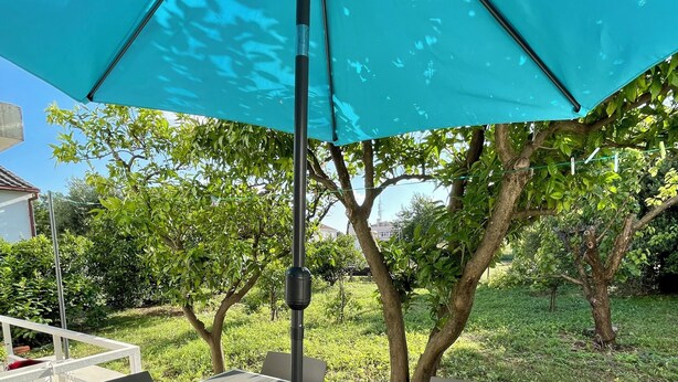 An outdoor patio with a table and chairs, a large umbrella, and a potted plant. - Apartment Paulina - 3-bedroom apartment in charming Trogir with WiFi, AC (Trogir)