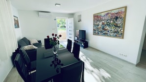 A modern dining area with a black table, chairs, and a vase of red roses. There is a painting on the wall and a television on a stand. - Apartment Paulina - 3-bedroom apartment in charming Trogir with WiFi, AC (Trogir)