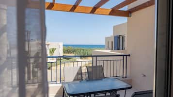 A balcony with a table and chairs, overlooking a coastal view.