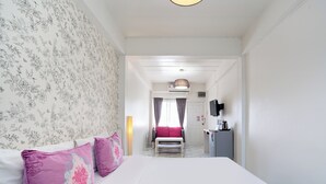 A bedroom with a bed, pillows, a bench, a TV, and a desk.