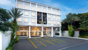 Een hotel met meerdere verdiepingen, een opvallende ingang, een parkeerplaats en veel groen eromheen.