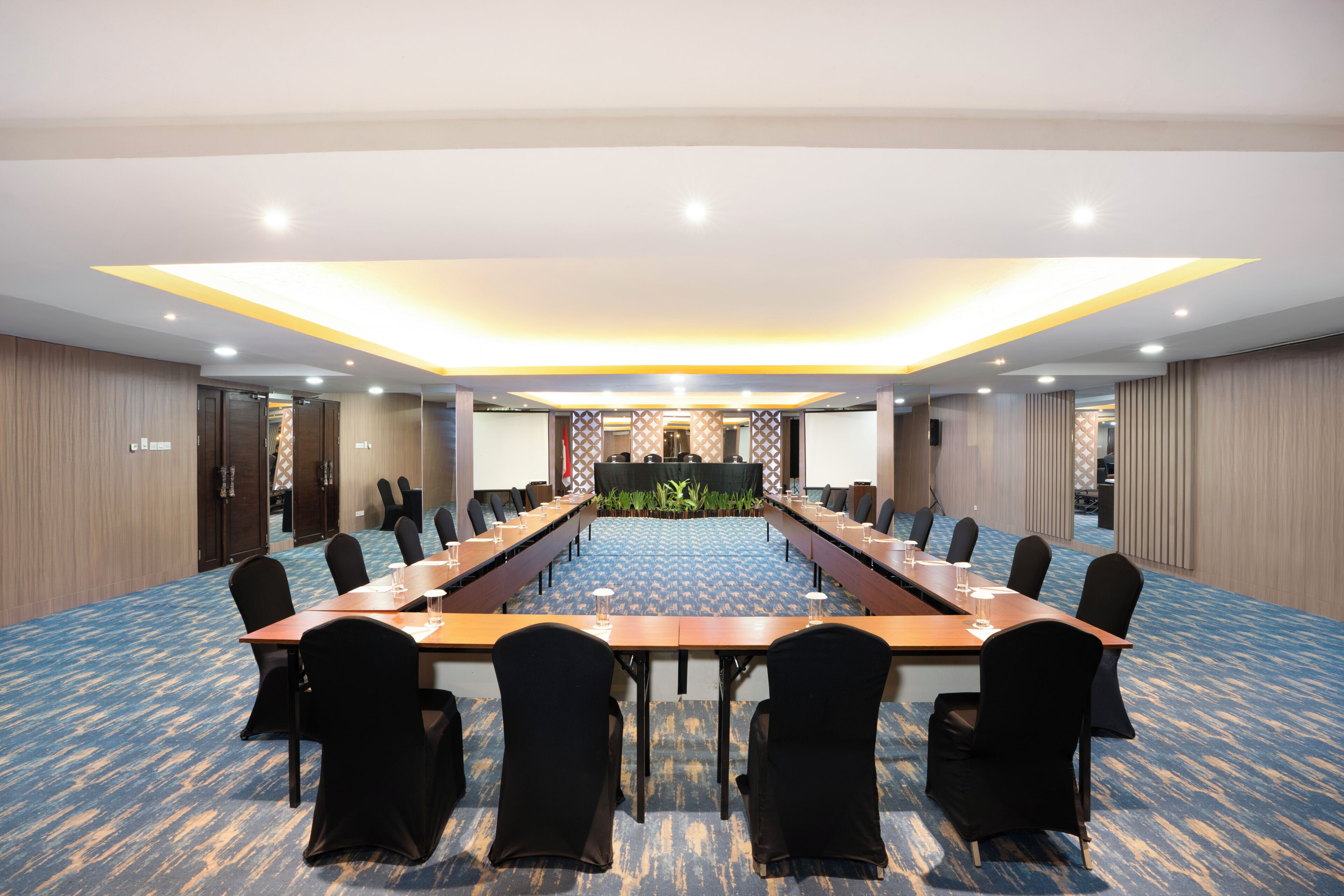 A conference room with a long table, chairs, and a carpeted floor.