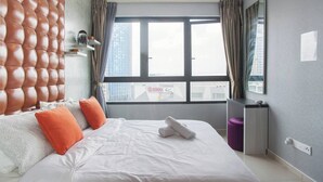A modern hotel room with a large bed, a tufted headboard, and a city view through the window. - I City Luxury Condo Shah Alam Smarthome (Shah Alam)