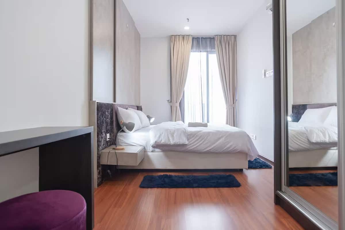 Une chambre à coucher moderne avec un lit, une table de chevet et un grand miroir.