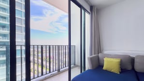 A balcony with a view of a cityscape and a modern sofa with a blue cover and a yellow pillow. - I City Luxury Condo Shah Alam Smarthome (Shah Alam)