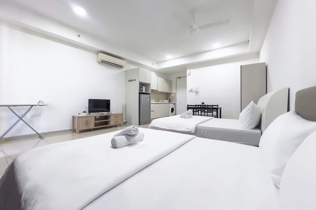 Une chambre d’hôtel avec deux lits, une télévision, un petit coin cuisine et un ventilateur de plafond.
