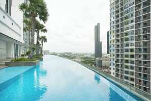 A rooftop infinity pool with a city view, surrounded by modern buildings and palm trees. - ICity Luxury Condominium Shah Alam (Shah Alam)