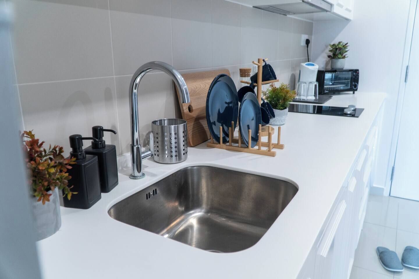 A modern kitchen with a stainless steel sink, a coffee machine, and a knife block.