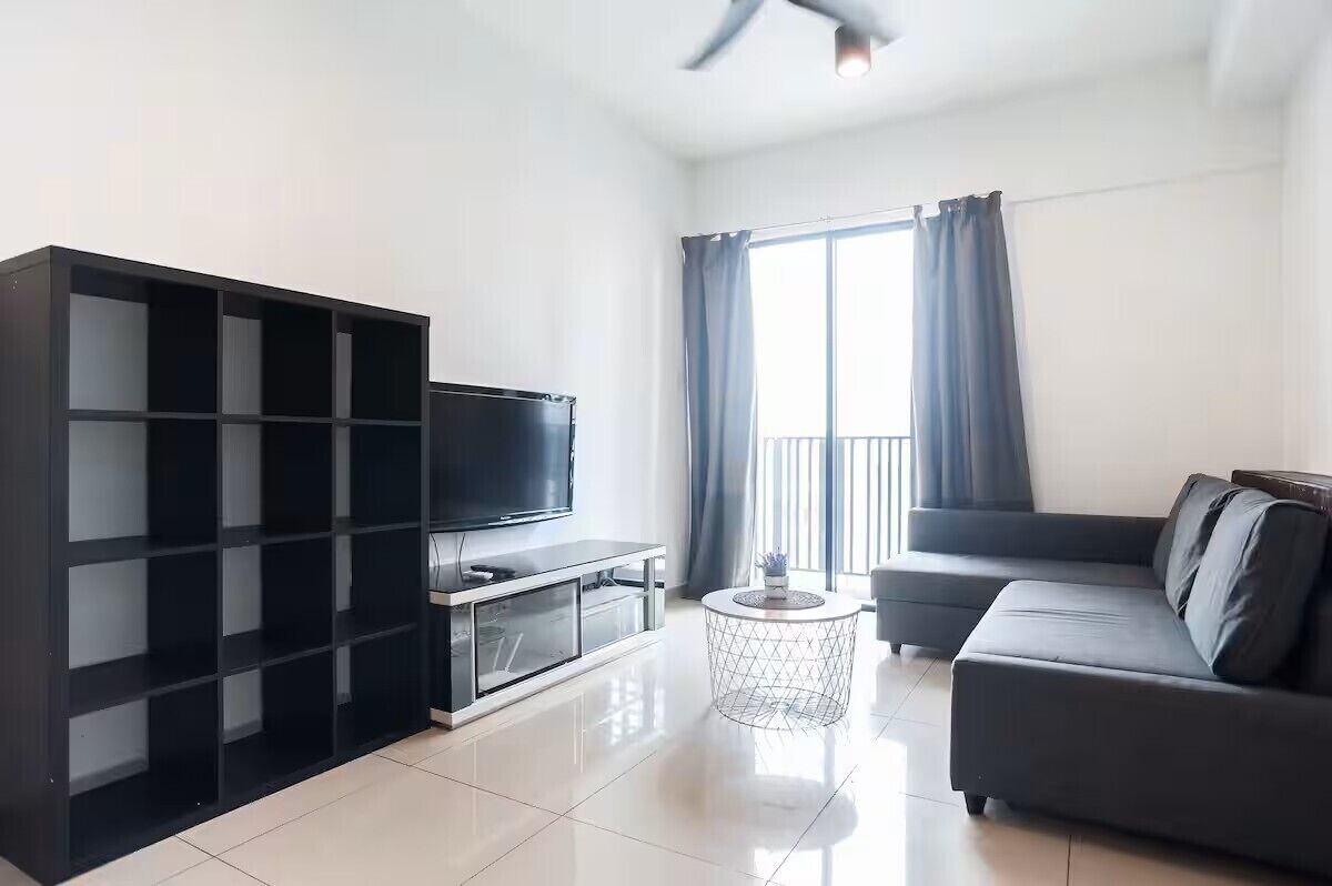 A modern living room with a flat-screen TV, a sofa, a coffee table, and a bookshelf.