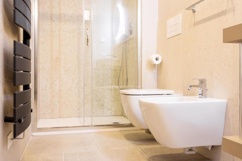 A modern bathroom with a glass shower enclosure, a white toilet, and a white sink.