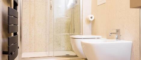 A modern bathroom with a glass shower enclosure, a white toilet, and a white sink.