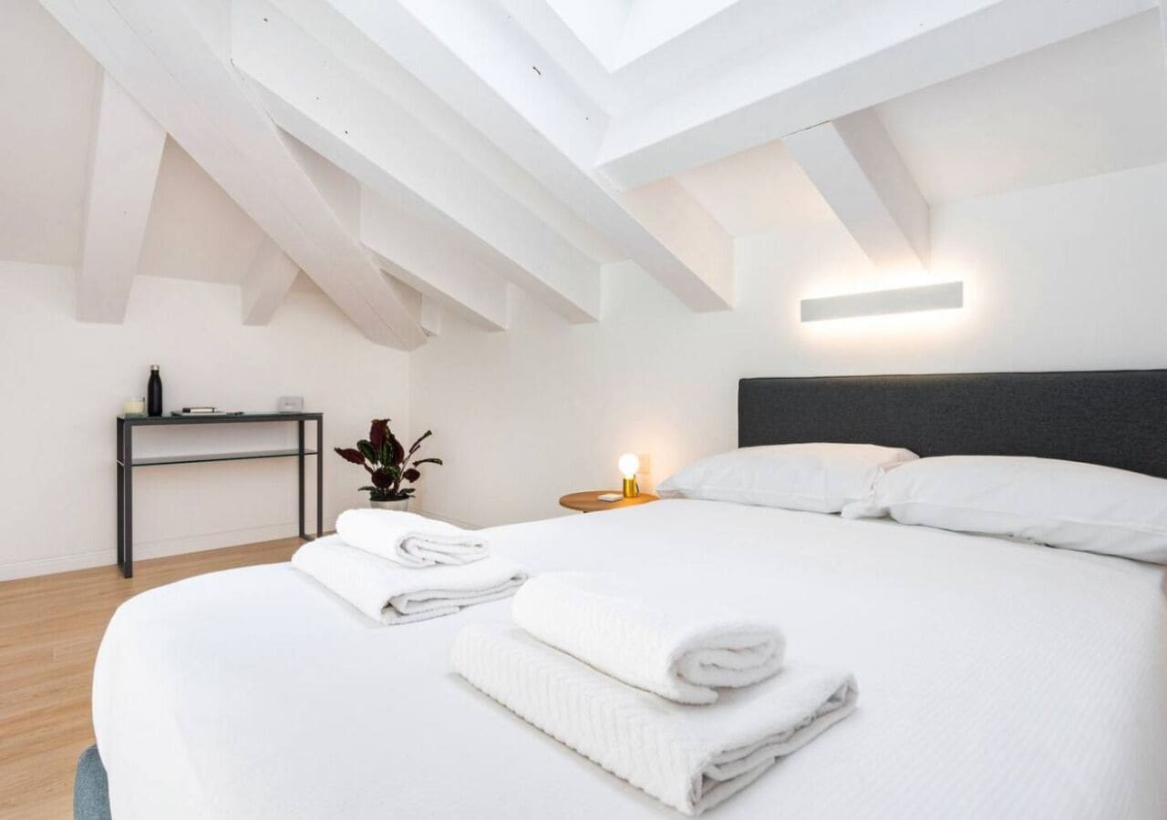 Une chambre à coucher moderne avec un grand lit, une table de chevet, une commode et une lucarne.