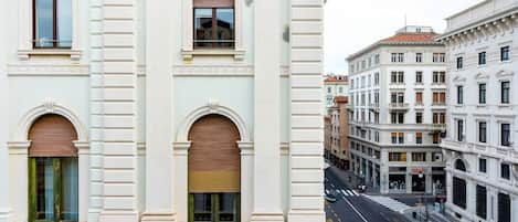 A street view of a building with classical architecture, featuring arched windows and a central entrance.