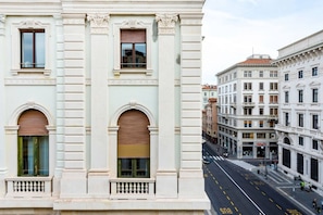 A street view of a building with classical architecture, featuring arched windows and a central entrance. - JOIVY Premium Apartments Trieste Mazzini (Trieste)